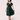 Woman posing in 1950s style emerald green swing dress with black basque waist and cuff details