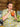 Woman in 1940s yellow floral dress sipping a tropical cocktail at a tiki bar