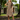 Woman in 1940s green floral tea dress with flutter sleeves posing in a park setting