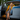 Woman sitting in vintage blue car wearing blue and yellow floral tea dress with mustard cardigan