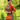 Blonde woman in 1940s amber floral dress, orange cardigan, and hat holding handbag