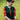 Blonde woman wearing forest green cable knit tank top over bright red floral tea dress